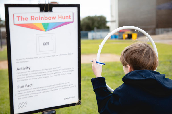  Child looking through the ring to find the next colour in the The Rainbow Hunt activity during the winter school holidays at Scienceworks.