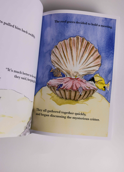 Open book displays an illustrated underwater scene with a large seashell surrounded by small fish.