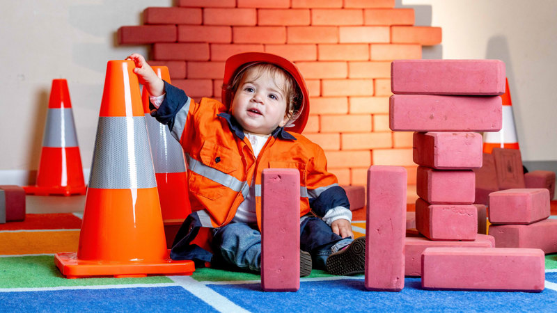Small child next to brick-like building blocks and traffic cones