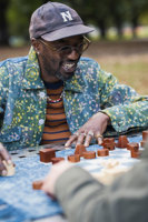 Maleik Njoroge smiles while playing chess with wooden pieces in the park.