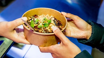 A closeup of dumplings being passed to a customer.