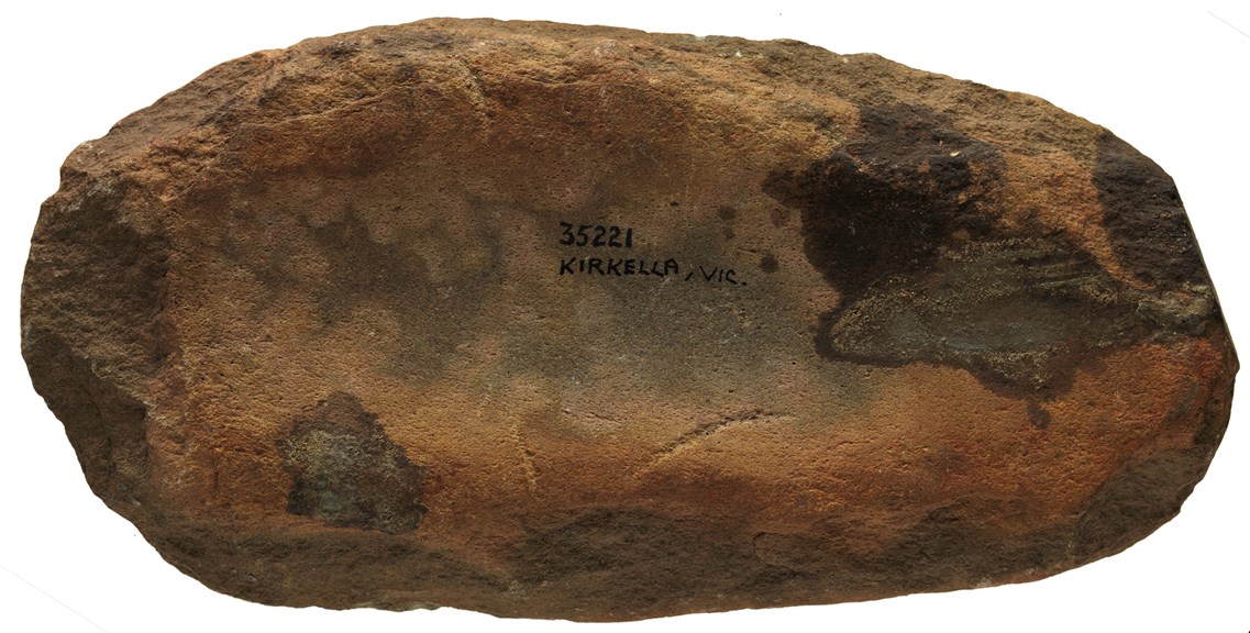 A large stone with a wide and long groove running through it. 