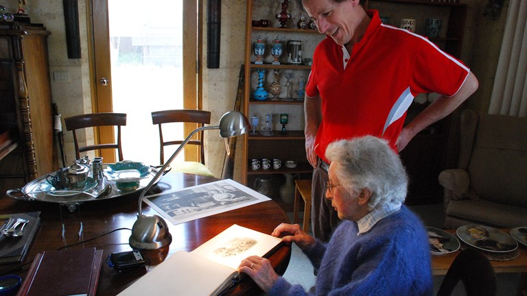 Will Twycross and his mother Mary, 2008, looking at an album of photographs surrounded by objects purchased by Will's great grandfather, John Twycross, at Melbourne's International Exhibitions.
