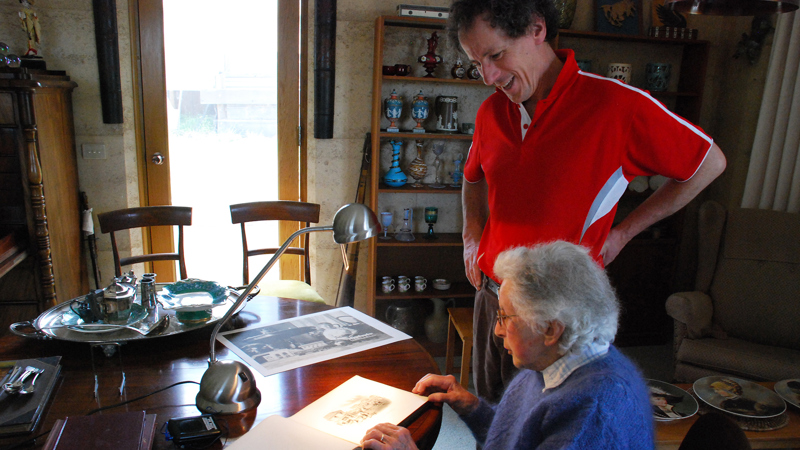Will Twycross and his mother Mary, 2008, looking at an album of photographs surrounded by objects purchased by Will's great grandfather, John Twycross, at Melbourne's International Exhibitions.