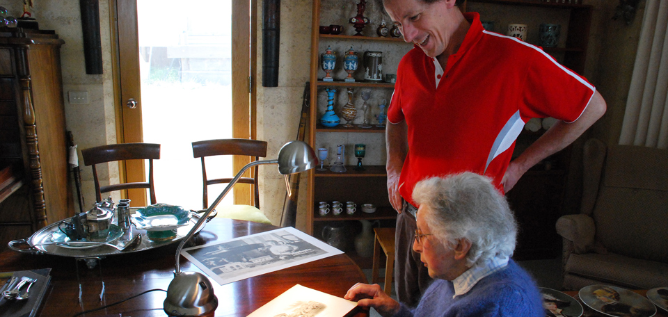 Will Twycross and his mother Mary, 2008, looking at an album of photographs surrounded by objects purchased by Will's great grandfather, John Twycross, at Melbourne's International Exhibitions.