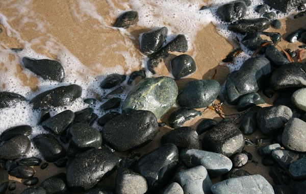 Greenstone pebbles on a sandy beach