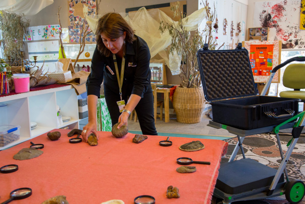 Outreach Program Presenter,  setting up fossils and magnifying glasses on a table at Child Care Centre.