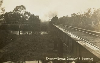 A steam locomotive crossing a rail bridge over the Goulburn River, Seymour, circa 1915