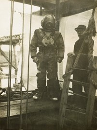 A suited diver with a metal helmet about to descend into the well of Pier 4 of the Tambo River Bridge on the Bairnsdale to Orbost line, 1914