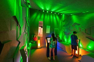 Children using interactives in a room with wall bathed in green light
