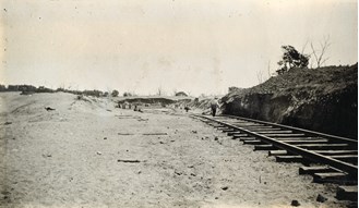 A railway track runs along the side of a cutting at the 65 mile ballast pit, Moama to Balranald line, circa 1923-26.