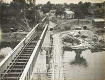 Constructing the rail bridge over the Murray River, Yarrawonga, circa 1930. The girder for the main spans is on the left and a temporary bridge with a construction tramway is on the right.