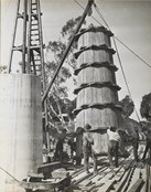 Workers guiding timber formwork into place as it is lifted by a crane during construction of the rail bridge over the Murray River, Yarrawonga, on the Yarrawonga to Oaklands line
