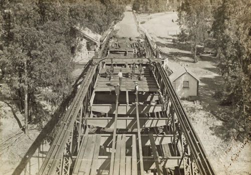Constructing the bridge over the Murray River on the Strathmerton to Tocumwal line, Tocumwal, 1906. Workers are reinstating the timber decking following strengthening of steel work.