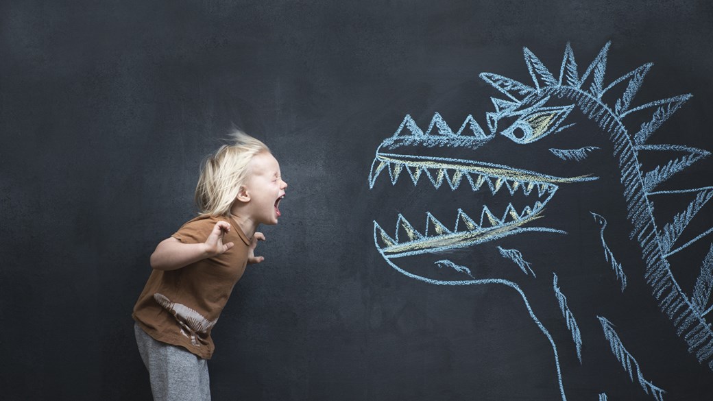 A boy yells at a chalk-drawn dinosaur on a blackboard.