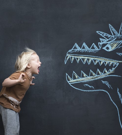 A boy yells at a chalk-drawn dinosaur on a blackboard.