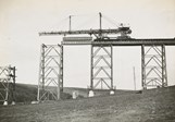 Construction of the Maribyrnong River Viaduct on the Albion to Broadmeadows line, Keilor East, 1928. A travelling crane is lowering a girder into position on top of two towers.