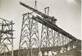 Construction of the Maribyrnong River Viaduct on the Albion to Broadmeadows line, Keilor East, 1928. A travelling crane has lowered a girder into position on top of two towers.