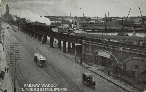 A steam locomotive hauling a passenger train, crossing Flinders Street Viaduct, circa 1910