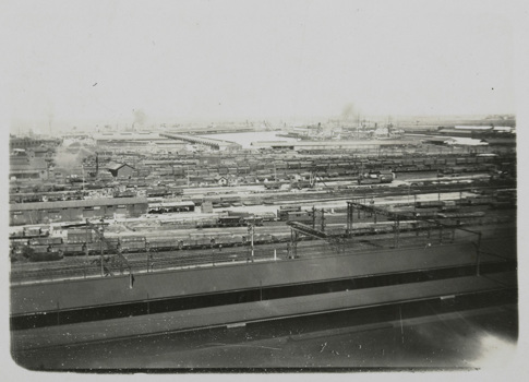 Spencer Street Station, post-1910. Covered railway platforms and railway yards. A large number of goods carriages in background. Railway line closest to covered platforms has been electrified.