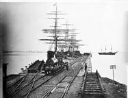 View of sailing ships berthed at Railway Pier, Williamstown, circa 1860s, with early Victorian Railways 0-6-0 type (later P class) goods locomotive in the foreground