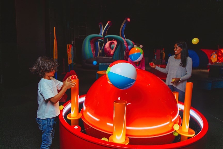 A child and parent using an interactive that makes objects float.