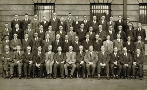 55 members of the Railway Construction Branch grouped outside the Victorian Railways Administration Building on Spencer Street, 1932