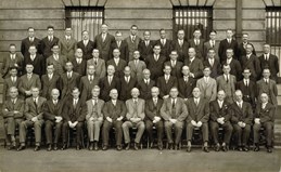 55 members of the Railway Construction Branch grouped outside the Victorian Railways Administration Building on Spencer Street, 1932