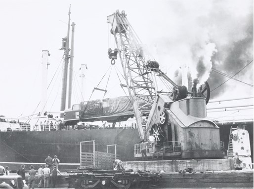Steam crane at North Wharf, West Melbourne, unloading L class mainline electric locomotives built for the Victorian Railways by General Electric Co Ltd., Preston, England, from a ship, circa 1952