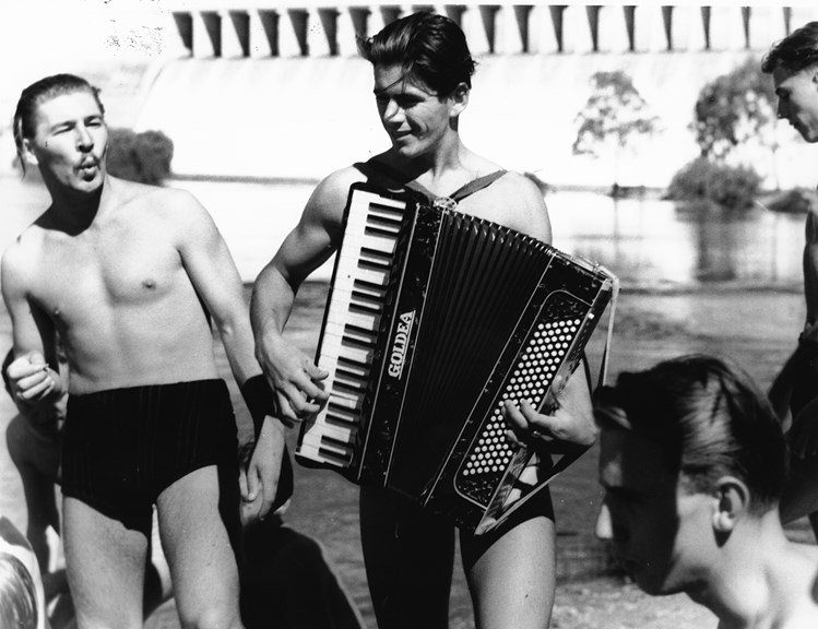 Migrants from Bonegilla Migrant Camp playing piano accordion on the banks of the Hume Weir.