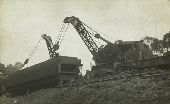 Two large cranes attempting to right an overturned railway carriage by means of cables around the carriage, circa 1910