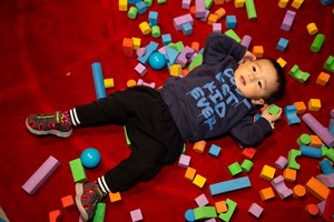 Boy lying on the floor amoungst colourful blocks