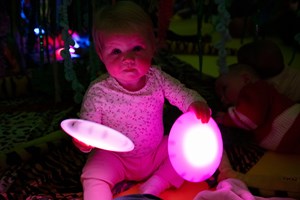 Baby holding to magenta glowing discs