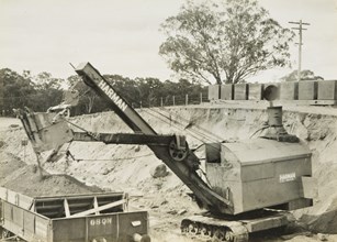 Construction of the Yarrawonga to Oaklands line, Yarrawonga, circa 1930. A Harman caterpillar-mounted steam shovel is loading ballast into rail trucks.