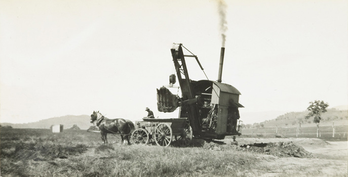 A steam shovel about to dump a load of earth into a horse-drawn wagon during the construction of the bridge over Sandy Creek, on the Sandy Creek deviation of the Wodonga to Tallangatta line, Tallangatta, circa 1930