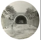 Tunnel construction on the South Kensington to West Footscray line, Footscray, 1928. A man with a theodolite stands in front of a tunnel.