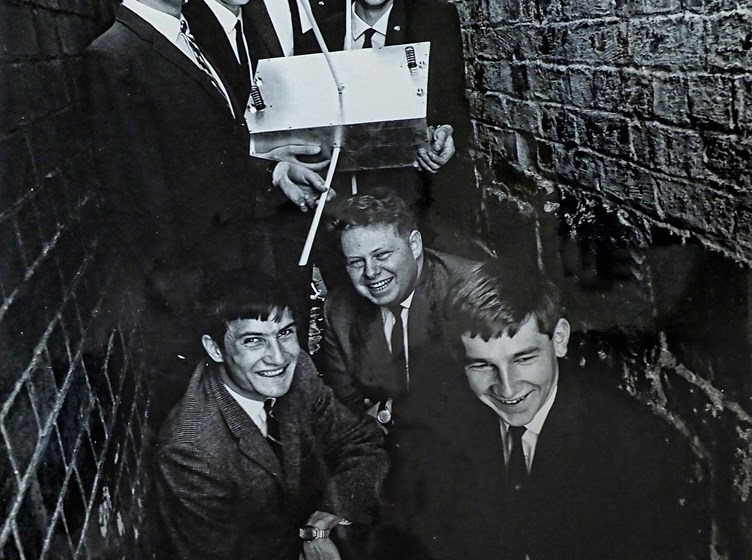 A group of young men in an alleyway holding a satellite. 