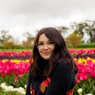 Portrait of a woman standing in a tulip field. She is wearing glassess