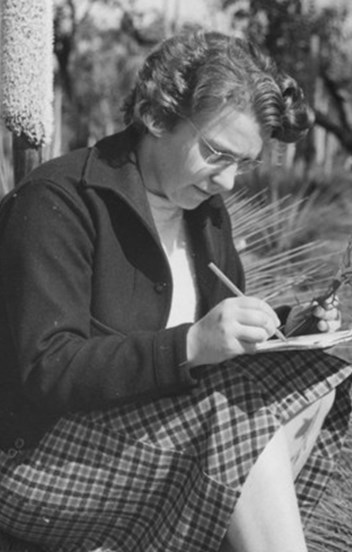 A woman sketches a plant cutting while sitting on a grass tree. 
