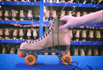 Still of a hand holding a roller skate in front of shelves of multiple roller skates