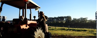 Still of a woman getting into a trackter in a country farm setting