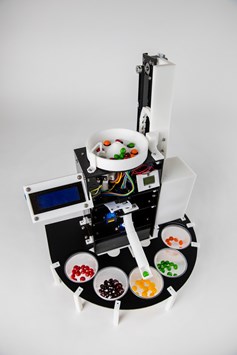 Close up image of Skittles Sorter's sorting arm with green skittle and visible electrical components