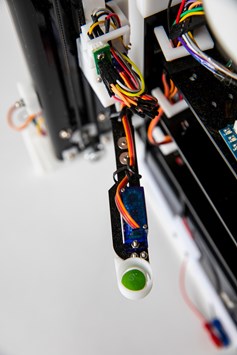 Close up image of Skittles Sorter's sorting arm with green skittle and visible electrical components