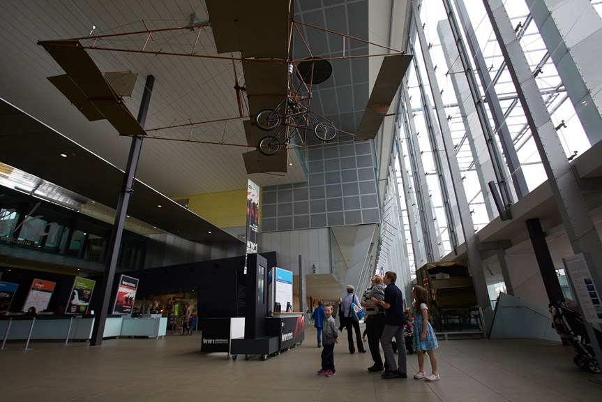 People in the Melbourne Museum foyer with a plane hanging above them