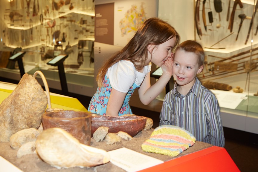 Girl whispering to boy in a museum exhibition