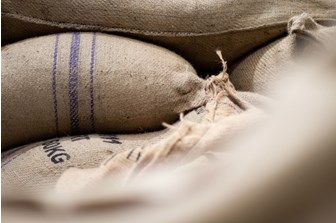 A close up of white hessian coffee bags with blue stripes. 