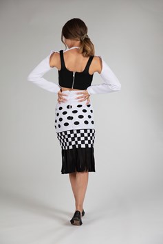 A girl is seen from the back modelling a long-sleeved black and white dress. It is detailed with complex cutouts and weaving to create circular and square patterns. 