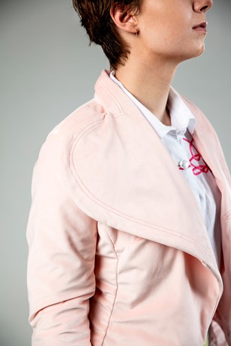 A profile view detail of a girl wearing a pink velvet jacket. The lapel has a distinct scallop shape.