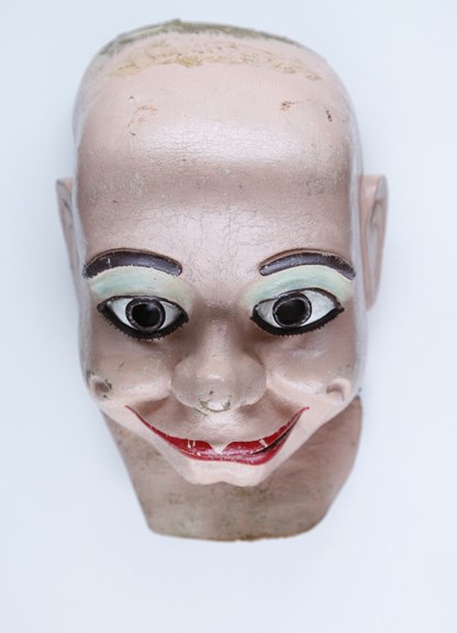 Painted rubber mask, moulded in the form of Gerry Gee 's face. The face of the mask is painted with red lips, moulded raised eyebrows and eyes painted in brown. 
