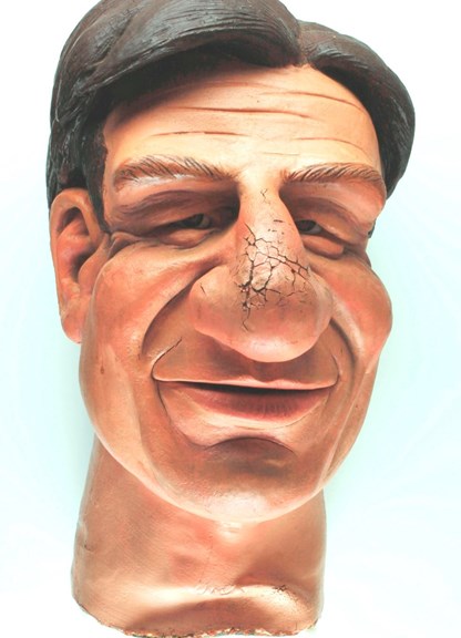 Life size puppet head, depicting a caricatural representation of a man. 